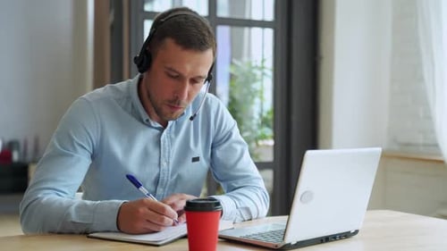 Young Adult Working at Home With Laptop and Headset