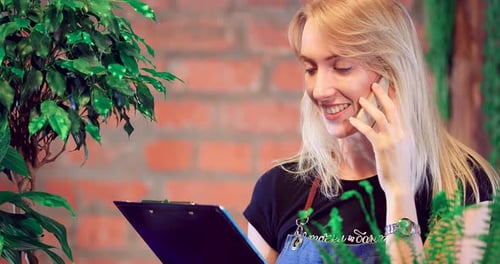 Woman Talking on Smartphone Holding Clipboard
