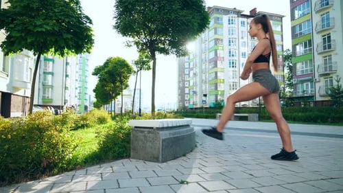 Young Woman Stretches Legs on Bench Outdoors