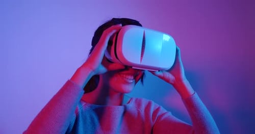 Woman Using Virtual Reality Headset in Colorful Lighting