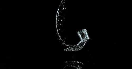 Glas Wasser prallt und spritzt auf schwarzem Hintergrund, Zeitlupe 4K