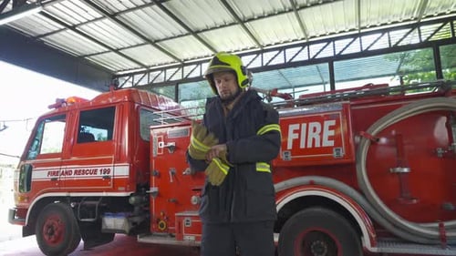 Firefighter Putting on Gloves Next to Firetruck