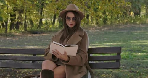 Woman Reading a Book on a Bench in Autumn