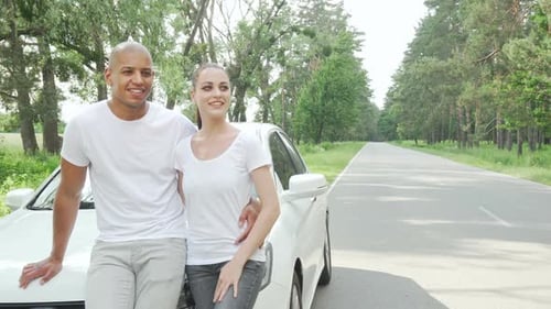 Smiling Couple Leaning on Car Near Forest Road