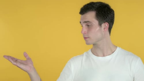 Young Adult Man Presenting on Yellow Background
