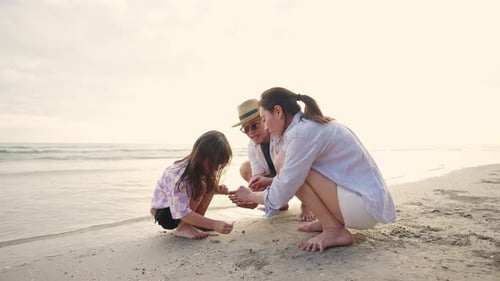 4K Parents with little daughter walking and playing together on the beach at summer sunset.