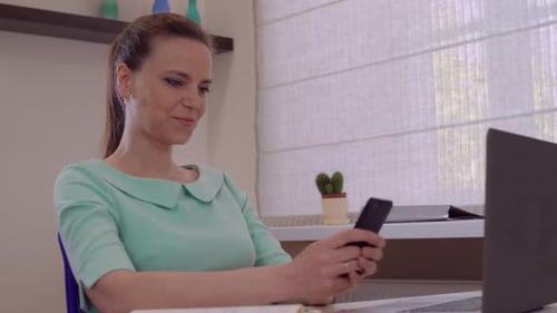 Young Woman Using Smartphone in Home Office
