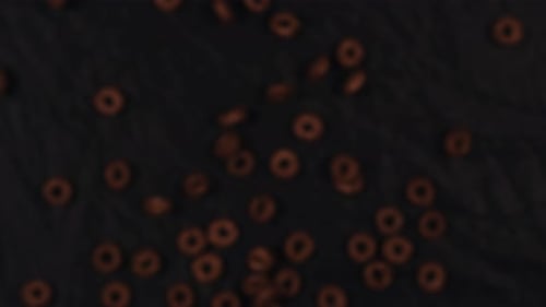 Chocolate Cereal Rings Falling on Dark Background