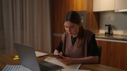 Young Woman Works on Phone and Laptop at Home