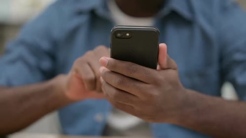 Close Up of Hands of African Man Using Smartphone