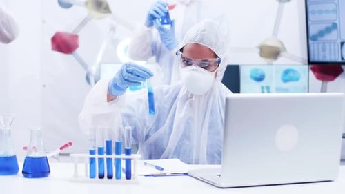 Wissenschaftlerin hält ein Reagenzglas mit Smoking Blue Fluid und Schreibformel