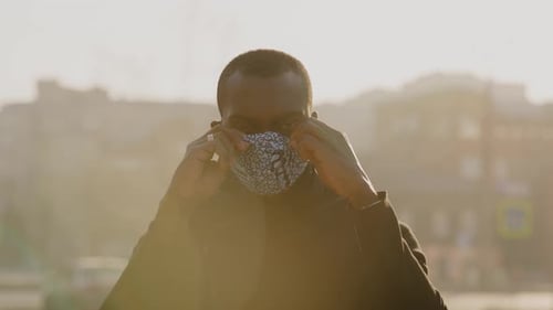 African American Man Out and About in the City Streets During the Day, Wearing a Face Mask Against