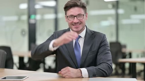 Businessman Reaches Out for Handshake in Modern Office
