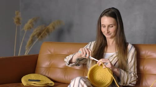 Woman Crocheting Yellow Yarn Bowl on Couch