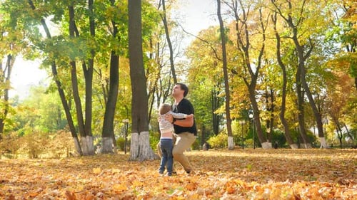 Video of Happy Young Father Playing with His Little Son and Raising Him in the Air at Autumn Park