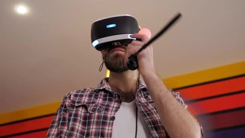 Un joven barbudo juega a videojuegos con un casco de realidad virtual