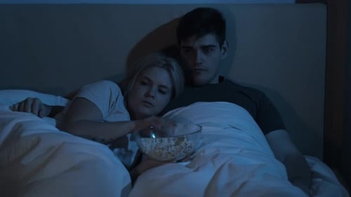 Intimate Couple Cuddles in Bed Watching Scary Movie