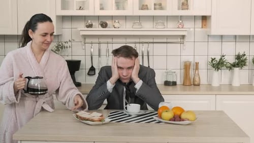 Tired Man Drinks Coffee at Kitchen Table