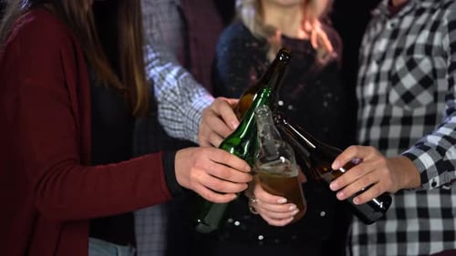 Un groupe d'amis tintent des verres avec des bouteilles de bière.