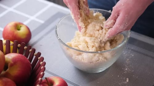 Hands Mixing Dough in Bowl with Apples