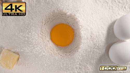 Raw Egg Yolk Falling into Flour
