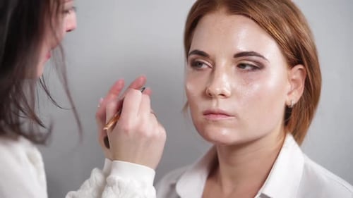 Makeup Artist Applying Eyeliner to Young Woman