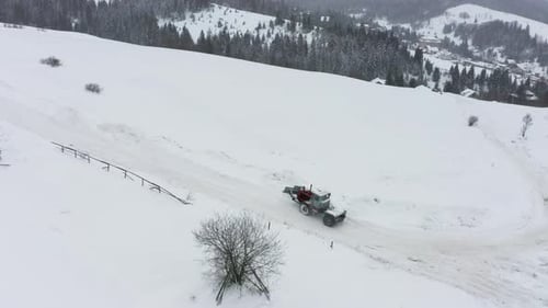The Tractor Removes Snow From the Snowcovered Road so That the Cars Can Pass