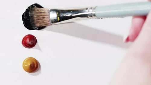 Brush Spreading Black Paint on White Surface