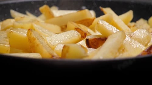 Cooking Fried Potato on Frying Pan. Roasting Sliced Potatoes