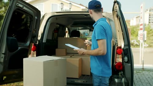 Slow Motion of Young Male Courier Working with Documents Checking Parcels in Van