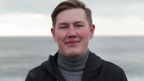 Portrait of Attractive Caucasian Man Smiling on Seaside Beach in Rain