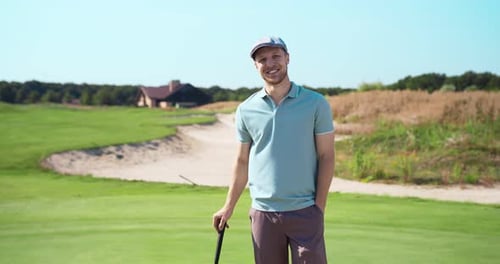 Portrait of Positive Male Caucasian Golf Player Smiling Standing with Golf Club at Golf Course