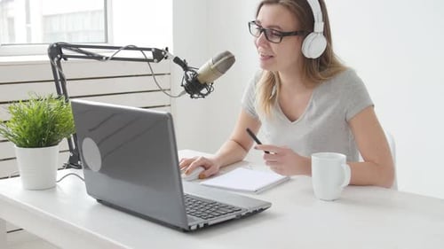 Young Cheerful Girl in the Studio Speaks Into a Microphone