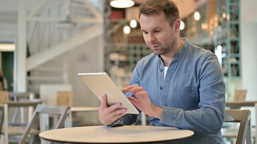 Digital Tablet Use By Attractive Casual Man in Cafe