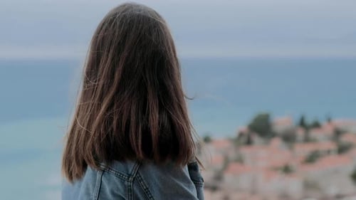 Woman Gazing at Coastal Island From Balcony