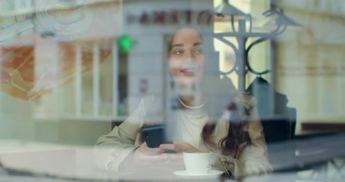 Young Woman Using Smartphone Drinking Coffee in Cafe Texting Sharing Messages on Social Media