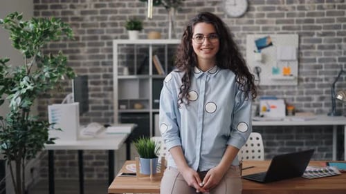 Portrait of Attractive Young Woman Standing in Office Alone Looking at Camera