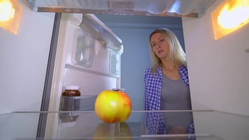 Woman Takes an Apple from Refrigerator