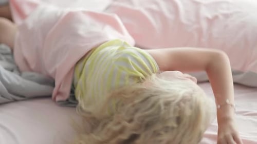Happy Blond Child Smiles on a Pink Bed