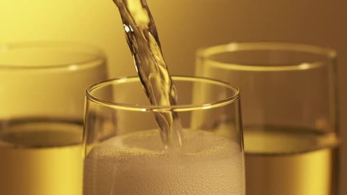Champagne Poured into Flutes Overflows with Bubbles