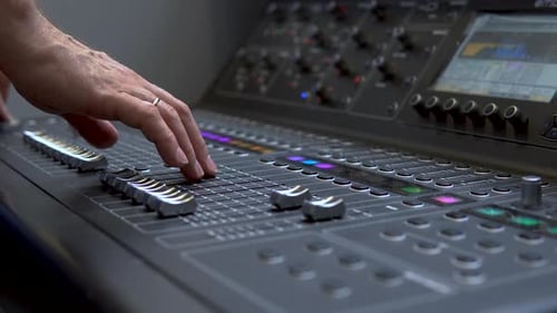 Man Works on a Professional Electronic Audio Mixer. A Control Panel for Tuning Sound Channels
