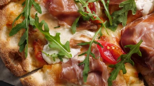 Pizza au prosciutto avec tomates au fromage strachatella et feuilles de roquette
