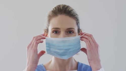 Woman Putting on a Light Blue Face Mask