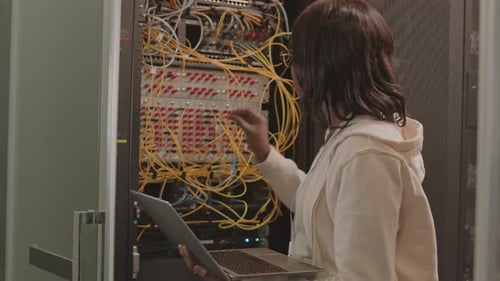 Woman Working on Laptop at Server Rack
