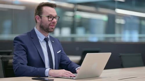 Professional Man Video Conferencing on Laptop in Office