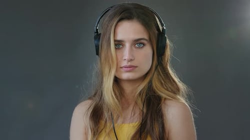 Studio Portrait Grauer Hintergrund Junge Schöne ernsthafte Studentin trägt Kopfhörer auf dem Kopf