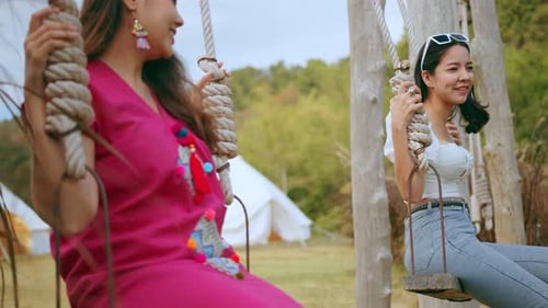 Women Relaxing on Swings in a Grassy Field