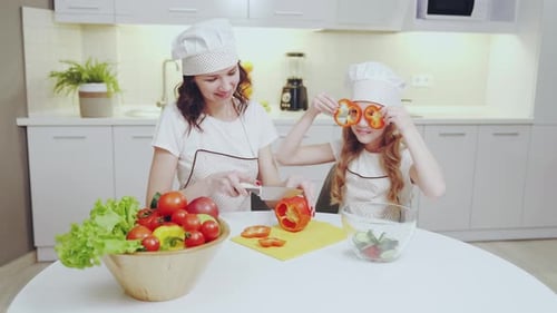 Cute Girl and Her Mother Cutting Red Pepper in Kitchen