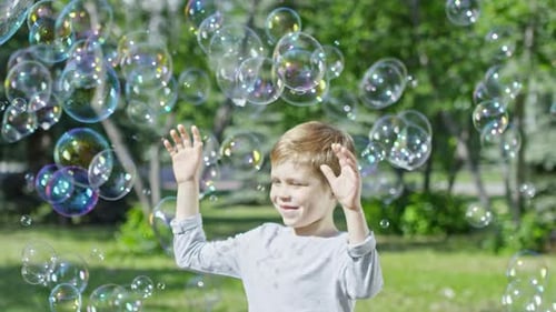 Happy Blonde Boy Enjoying Soap Bubbles