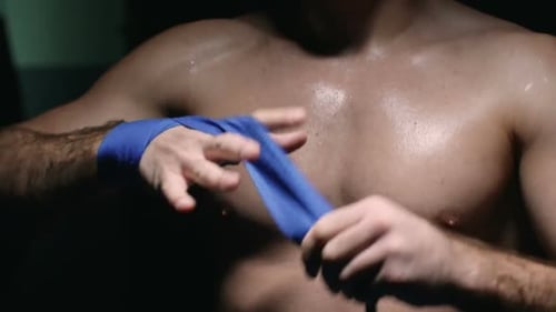 Muscular Man Wraps Hand with Blue Bandage